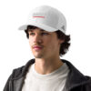 A man wearing a white hat with red lettering.
