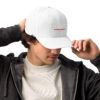 A man in a white hat putting on his baseball cap.